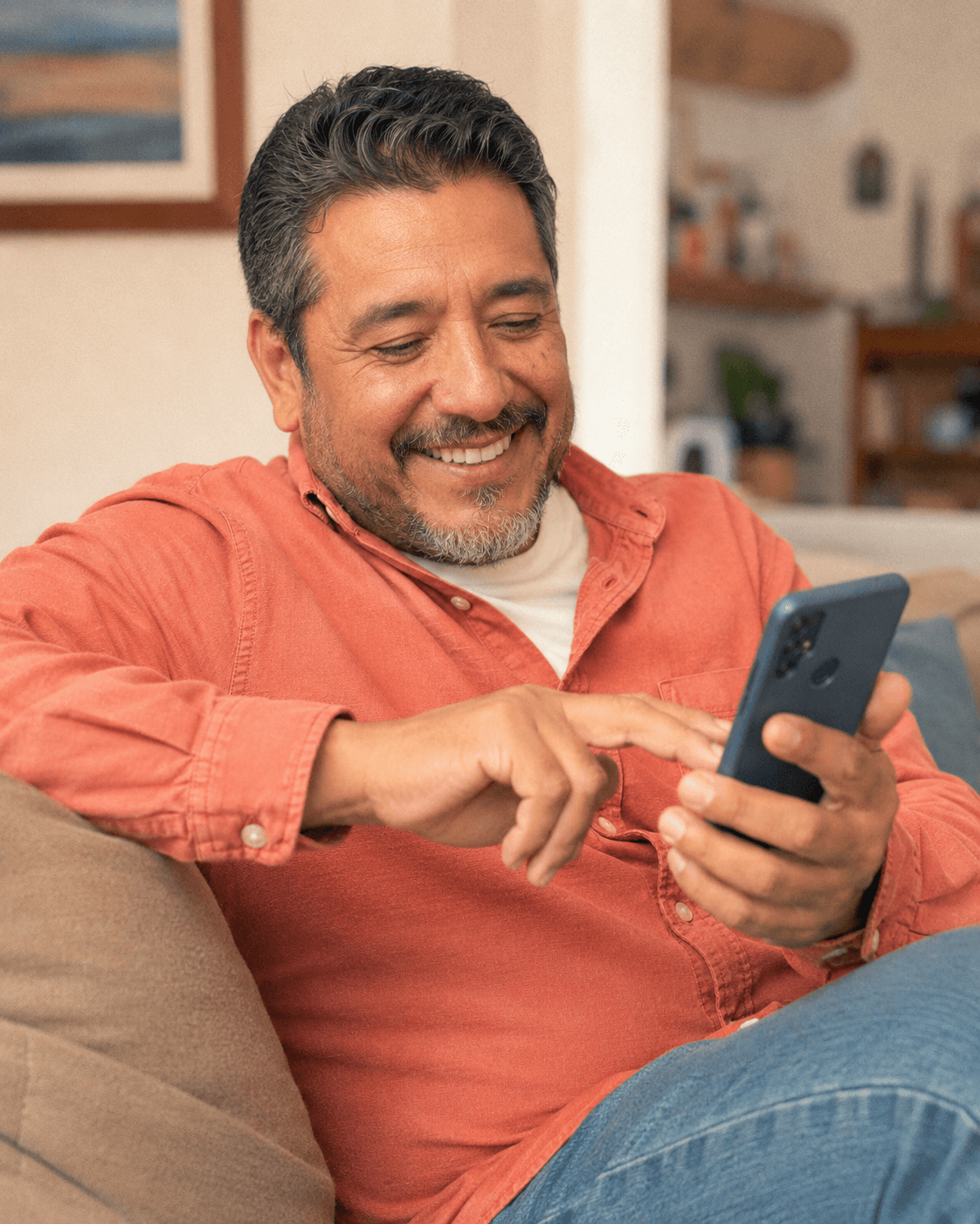 A smiling middle-aged man adding a photo to the family newsletter from his phone on the couch